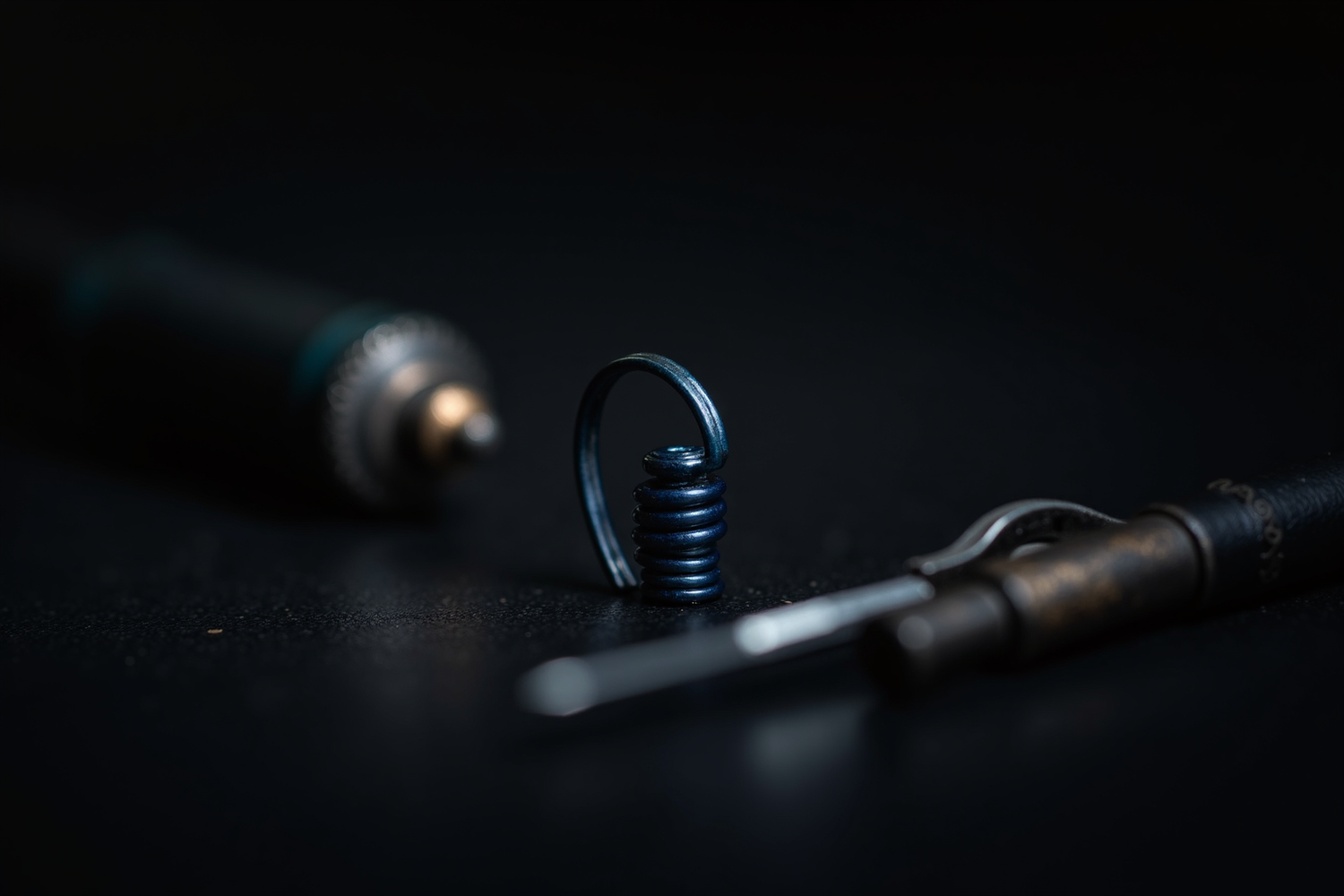 Macro editorial photograph of a blued hairspring coil resting on a watchmaker's bench beside antique tweezers — Grandeur USA